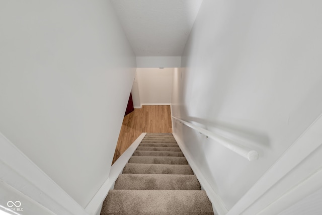 stairs with wood-type flooring and vaulted ceiling