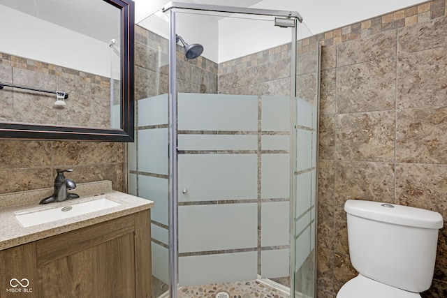 bathroom with walk in shower, tile walls, vanity, and toilet