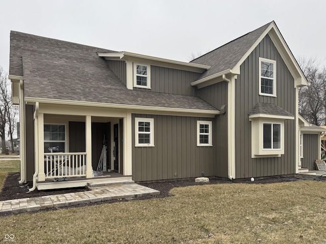 rear view of house featuring a yard and a porch