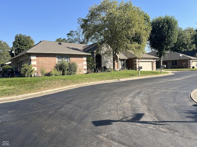 view of front of property with a front yard, brick siding, and an attached garage