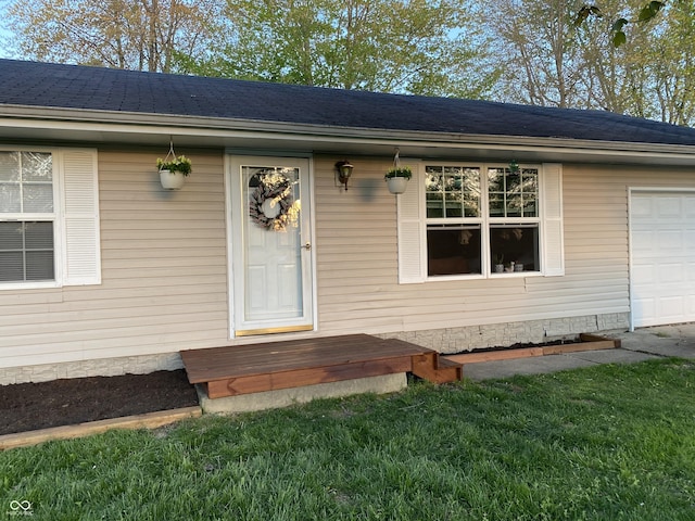 view of exterior entry featuring a garage and roof with shingles