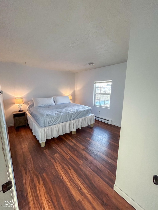 bedroom with a textured ceiling, dark wood-style flooring, visible vents, baseboards, and baseboard heating