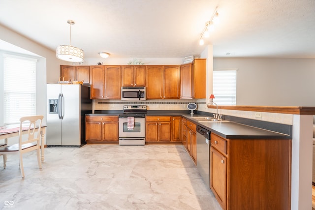 kitchen with tasteful backsplash, dark countertops, appliances with stainless steel finishes, brown cabinets, and a sink