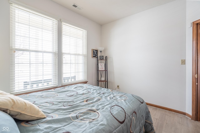 bedroom with light wood-style flooring, visible vents, and baseboards