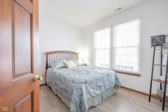 bedroom with light wood-style flooring, visible vents, and baseboards