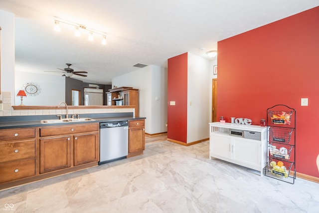 kitchen with dark countertops, visible vents, stainless steel dishwasher, brown cabinetry, and a sink