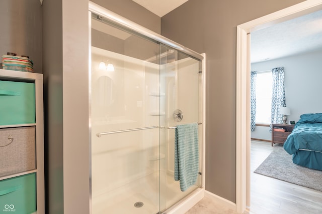 bathroom featuring a stall shower, baseboards, and wood finished floors