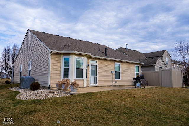 rear view of property featuring a yard, roof with shingles, a patio, and fence