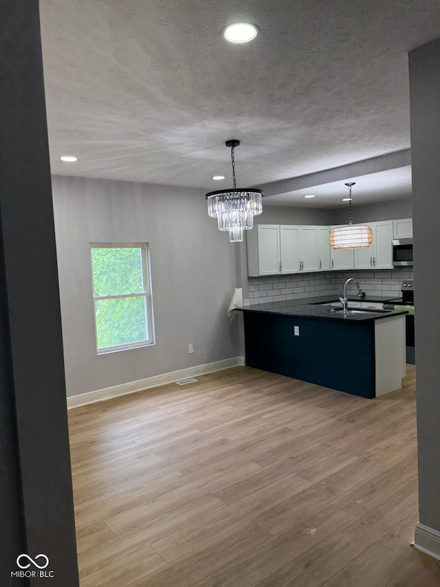 2312 Fletcher St, Anderson, IN 46016 - kitchen featuring appliances with stainless steel finishes, dark countertops, a chandelier, white cabinetry, and a textured ceiling