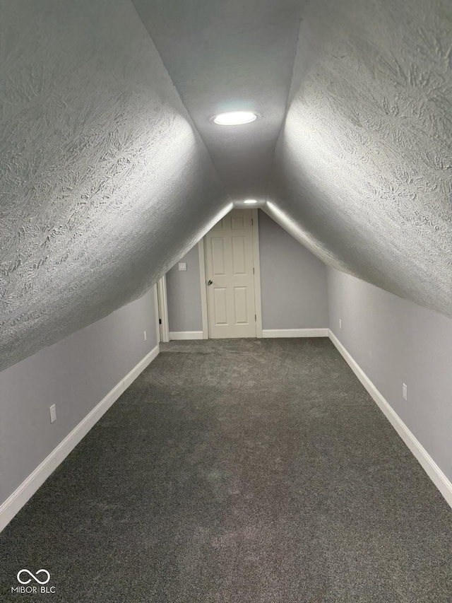 2312 Fletcher St, Anderson, IN 46016 - additional living space with a textured ceiling, vaulted ceiling, baseboards, and dark colored carpet