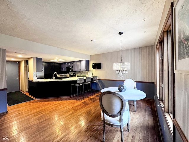 dining area with a notable chandelier, a textured ceiling, and hardwood / wood-style floors