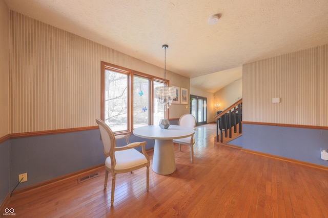 dining area with a notable chandelier, visible vents, a textured ceiling, and wood-type flooring