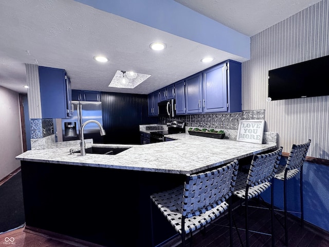 kitchen with blue cabinets, a sink, stainless steel appliances, a peninsula, and light countertops