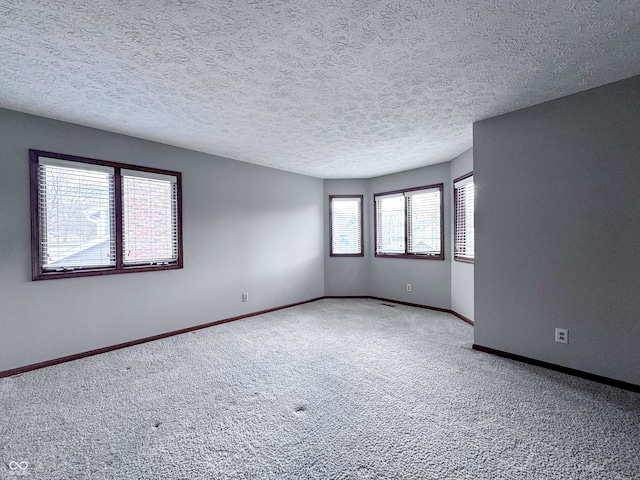 empty room featuring carpet flooring, a textured ceiling, and baseboards