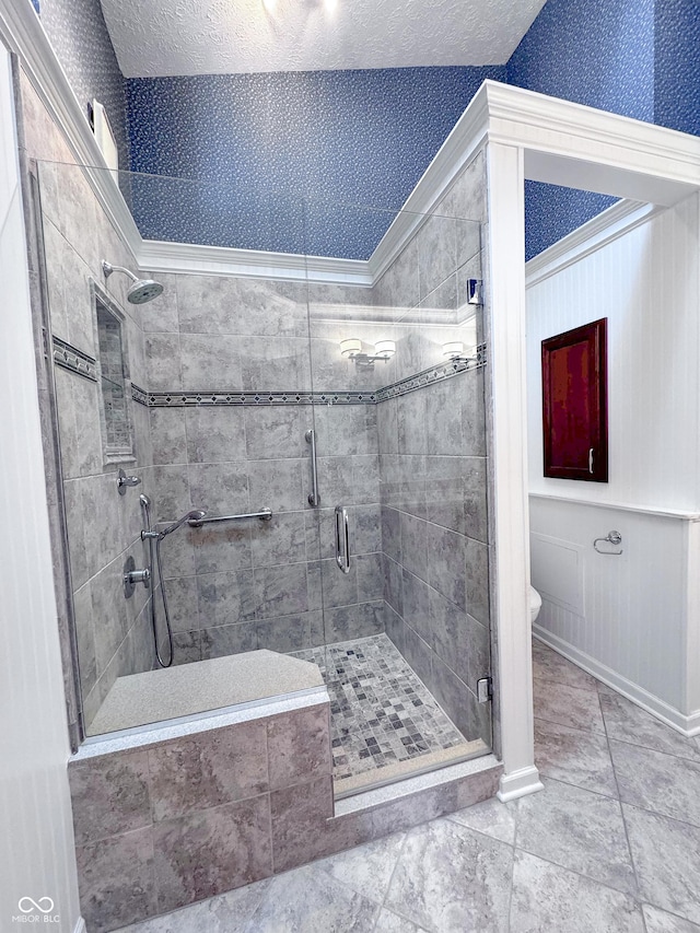 bathroom with a textured ceiling, toilet, a stall shower, and wallpapered walls