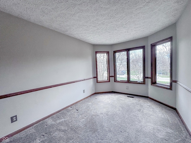 carpeted empty room with visible vents, baseboards, and a textured ceiling