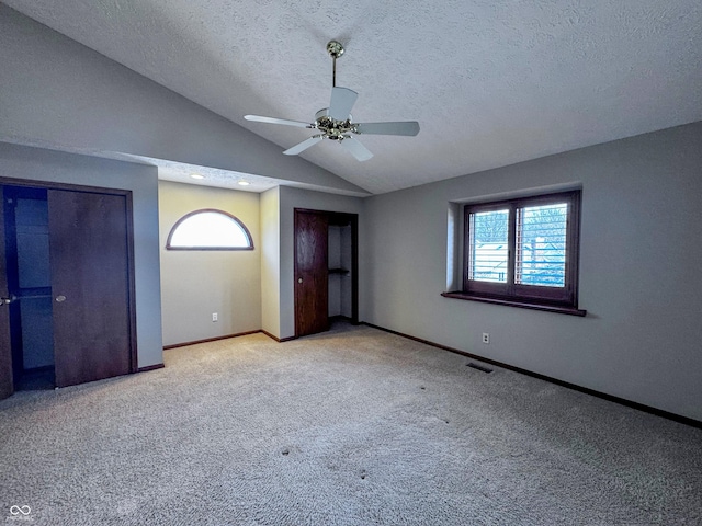 unfurnished bedroom with visible vents, multiple windows, lofted ceiling, and multiple closets