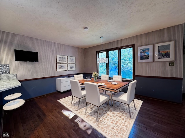 dining room with hardwood / wood-style floors, baseboards, and a textured ceiling