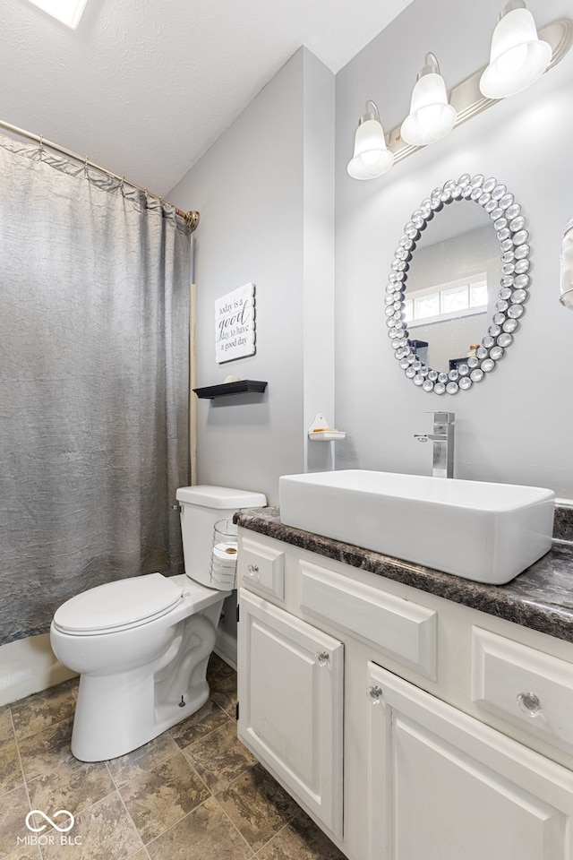 bathroom with stone finish floor, vanity, and toilet