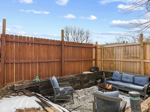 snow covered patio with an outdoor living space with a fire pit and a fenced backyard