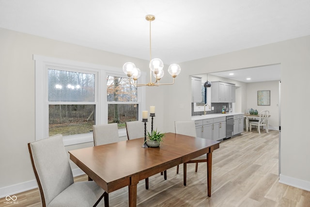 dining room with an inviting chandelier, sink, and light hardwood / wood-style floors