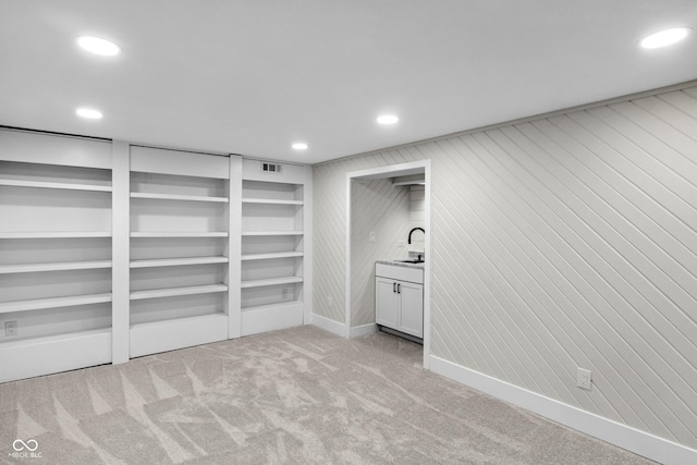 basement with sink and light carpet