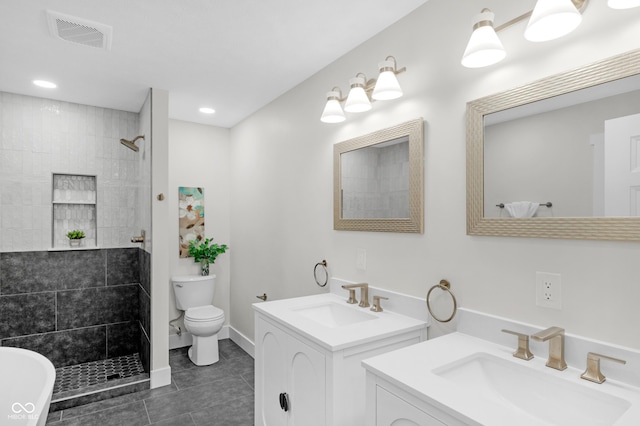 bathroom featuring tile patterned flooring, vanity, a tile shower, and toilet