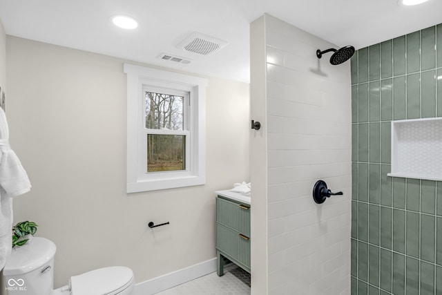 bathroom featuring vanity, tiled shower, tile patterned floors, and toilet