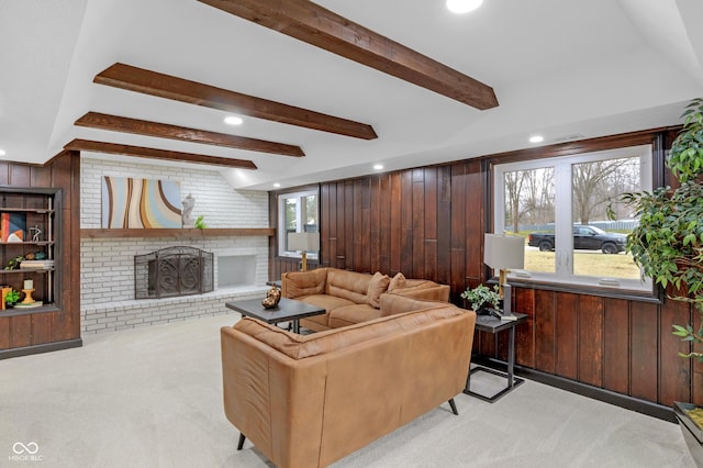 carpeted living room with beamed ceiling, a brick fireplace, and wood walls