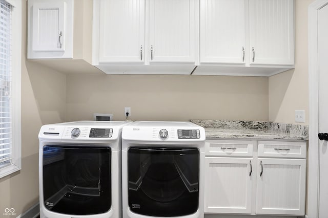 laundry area featuring separate washer and dryer and cabinets