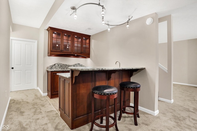 bar featuring light stone countertops, sink, and light carpet