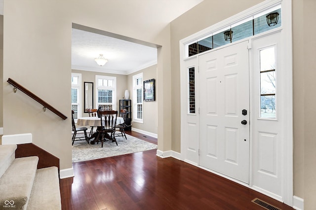 foyer entrance with crown molding and dark hardwood / wood-style floors