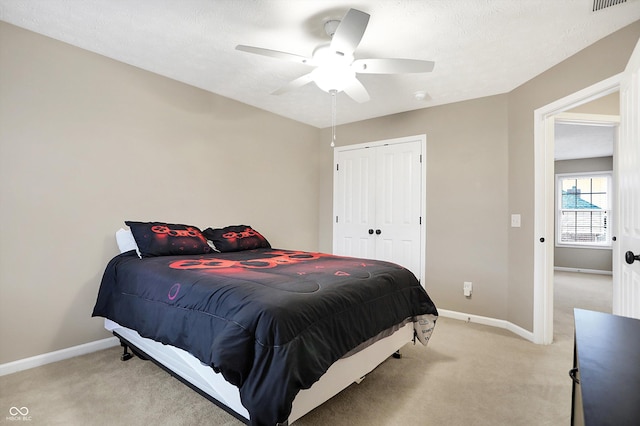 bedroom with ceiling fan, light colored carpet, a closet, and a textured ceiling