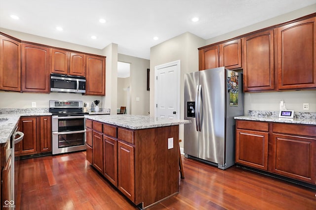 kitchen with appliances with stainless steel finishes, dark hardwood / wood-style floors, and light stone countertops