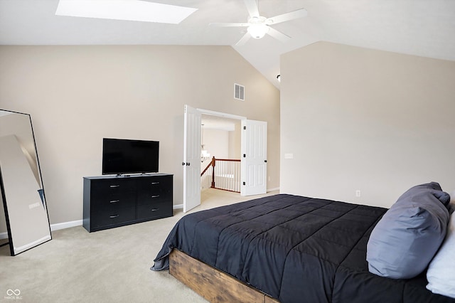 bedroom with ceiling fan, light colored carpet, high vaulted ceiling, and a skylight