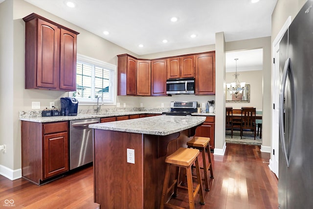 kitchen with dark wood-type flooring, a breakfast bar, sink, a center island, and stainless steel appliances