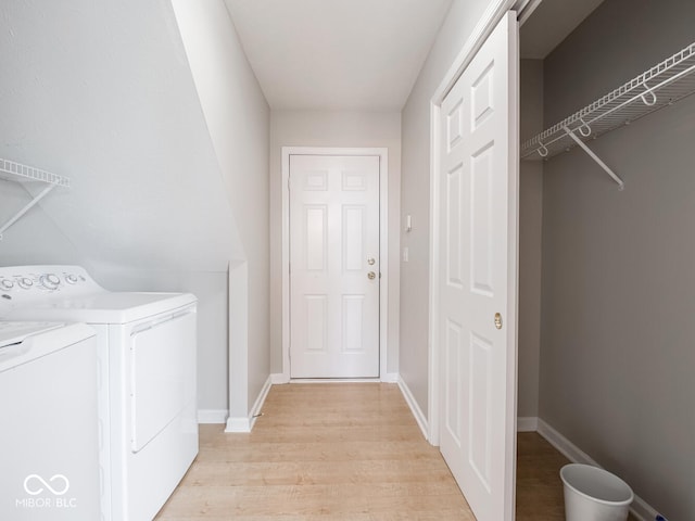 washroom with baseboards, laundry area, washer and clothes dryer, and light wood-style floors