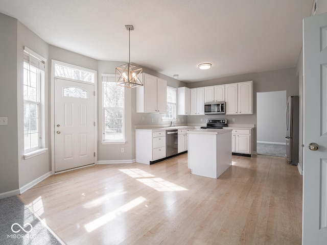 kitchen with light wood finished floors, white cabinetry, appliances with stainless steel finishes, and a center island