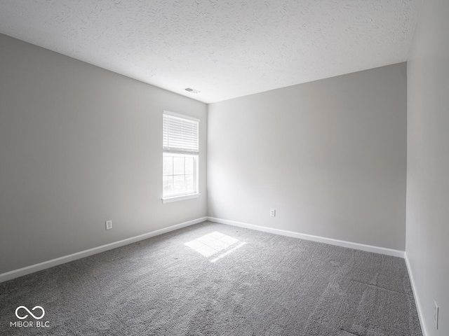 carpeted spare room with baseboards, visible vents, and a textured ceiling