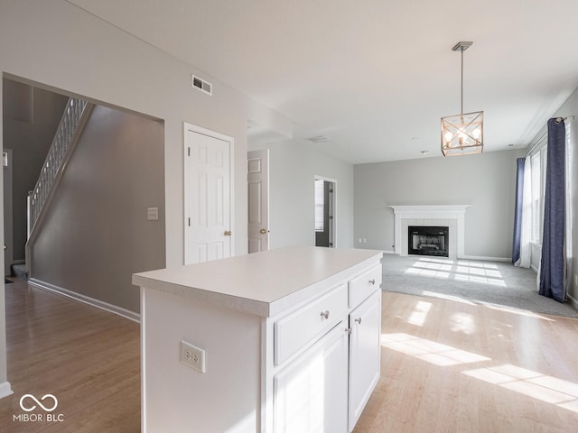 kitchen featuring light wood-style floors, a fireplace, visible vents, and light countertops