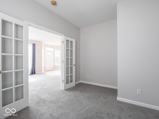 carpeted spare room featuring baseboards, a textured ceiling, and french doors