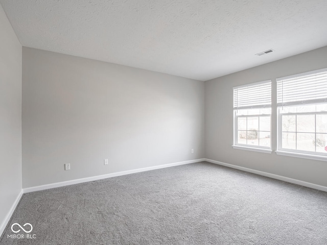 carpeted empty room featuring visible vents, a textured ceiling, and baseboards