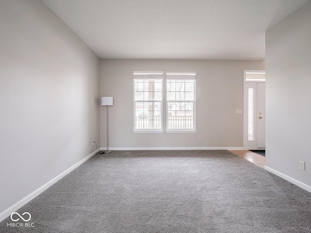 carpeted empty room featuring baseboards