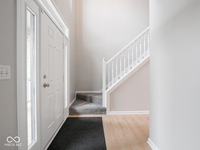 entryway with wood finished floors, baseboards, and stairs