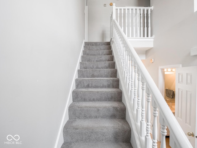 stairway featuring a high ceiling and baseboards