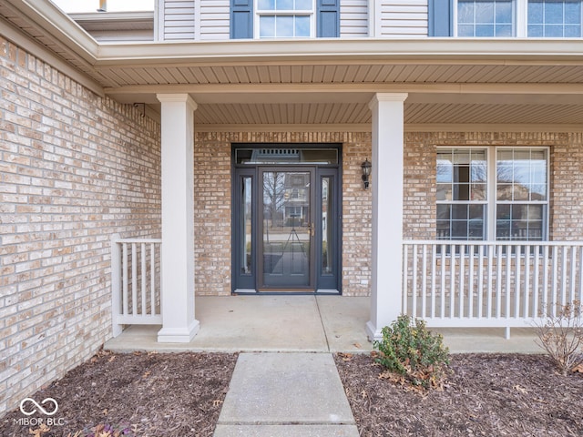 view of exterior entry with covered porch and brick siding