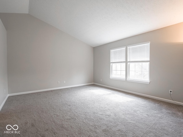 carpeted empty room featuring baseboards, vaulted ceiling, and a textured ceiling