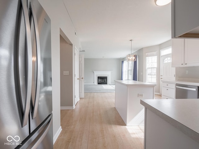 kitchen featuring a fireplace, a kitchen island, white cabinets, appliances with stainless steel finishes, and light wood finished floors