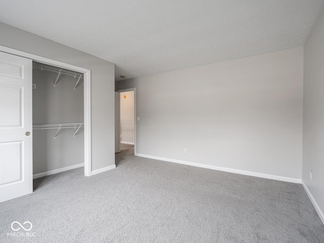 unfurnished bedroom featuring a textured ceiling, a closet, baseboards, and carpet flooring