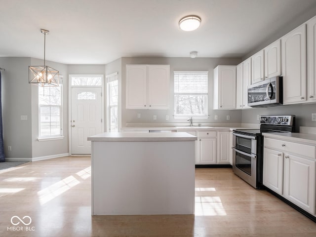 kitchen with white cabinets, stainless steel appliances, hanging light fixtures, and a center island